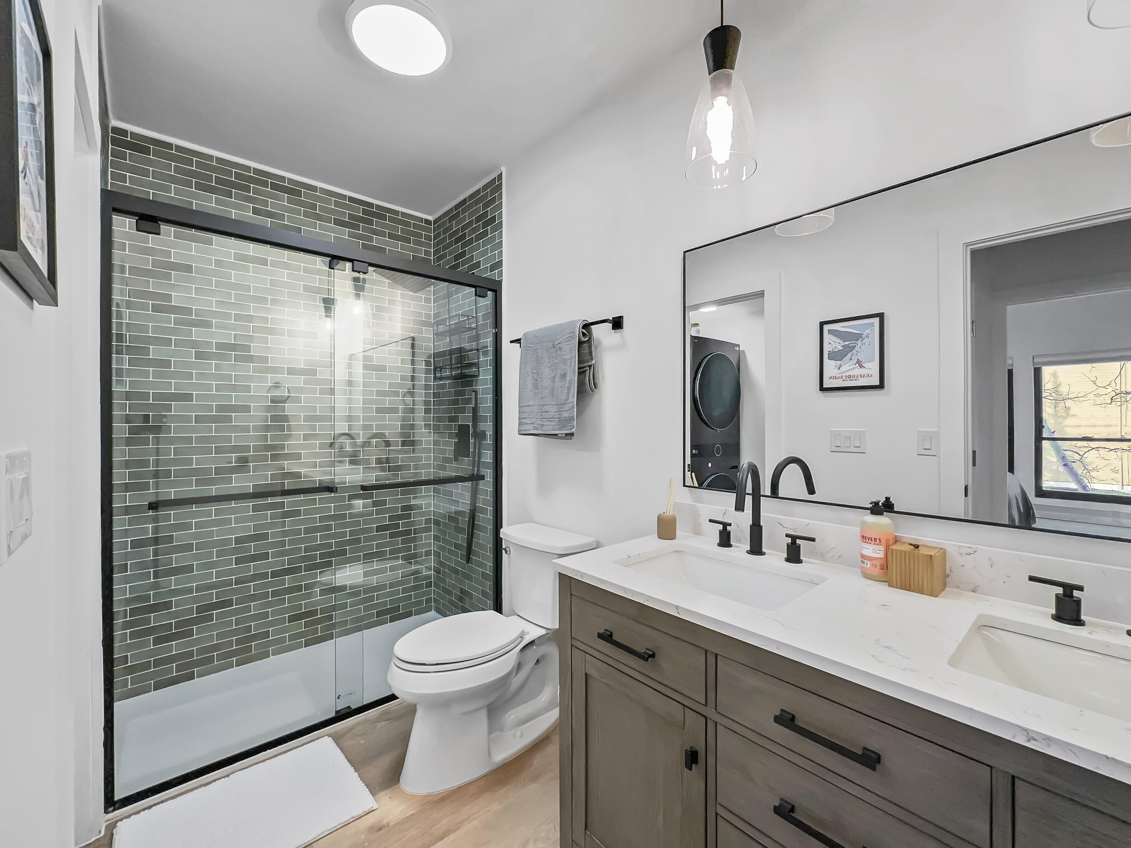 Une salle de bain moderne avec une douche à parois de verre, des toilettes, un lavabo avec un grand miroir et des meubles en bois.