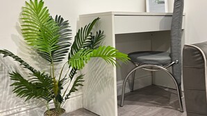 A corner of a room with a potted plant, a chair, and a white cabinet.