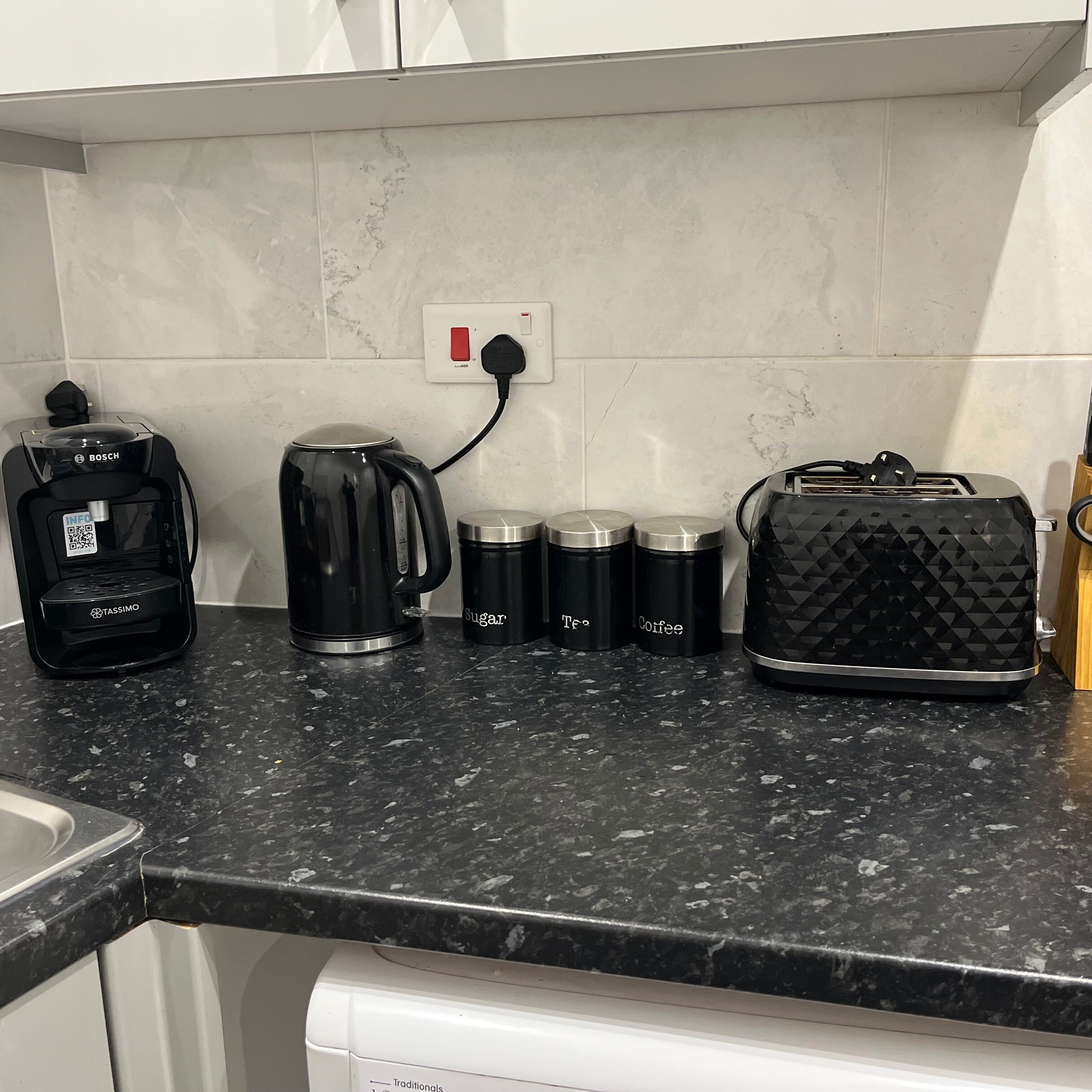 Eine Küchenarbeitsplatte mit Kaffeemaschine, Wasserkochern und Aufbewahrungsbehältern.