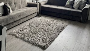 A modern living room with two grey sofas, a fluffy grey rug, and a floor lamp.