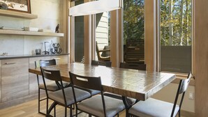 A modern kitchen with a large dining table, built-in cabinets, and a hanging light fixture. - Vail Ski Resort Valley Condos (Vail)