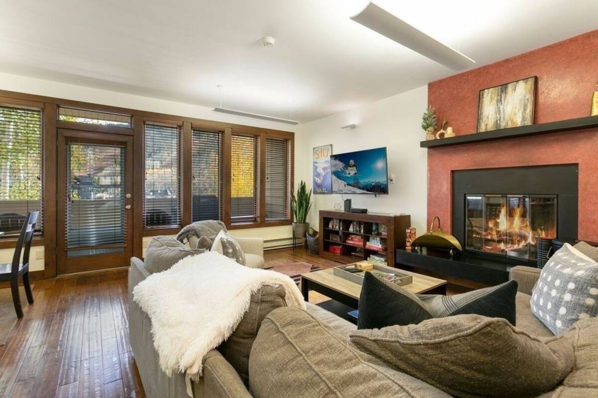 A living room with a fireplace, a sofa, a coffee table, and a bookshelf.