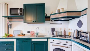 Une cuisine compacte équipée d’un four à micro-ondes, d’une cuisinière, d’un four et de divers ustensiles de cuisine.