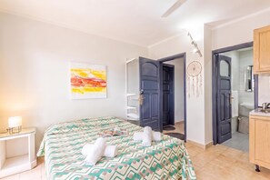 Een hotelkamer met een bed, nachtkastje met lamp, een wanddecoratie en een dromenvanger.