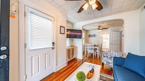 A spacious living room with a wooden floor, a ceiling fan, a TV mounted on the wall, and a dining area with a table and chairs. - 2nd Floor 2BR/1BA Getaway – Short Walk to Beach & Boardwalk! (Ocean City)