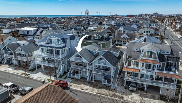 A coastal residential area with a mix of single and multi-story houses, a prominent Ferris wheel in the background, and a clear view of the ocean. - 2nd Floor 2BR/1BA Getaway – Short Walk to Beach & Boardwalk! (Ocean City)