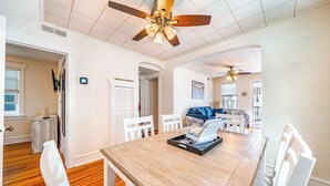 A spacious living room with a wooden dining table, white chairs, a blue sofa, and a ceiling fan. - 2nd Floor 2BR/1BA Getaway – Short Walk to Beach & Boardwalk! (Ocean City)