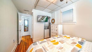 A bedroom with a bed, a television, a washing machine, and a window with blinds. - 2nd Floor 2BR/1BA Getaway – Short Walk to Beach & Boardwalk! (Ocean City)