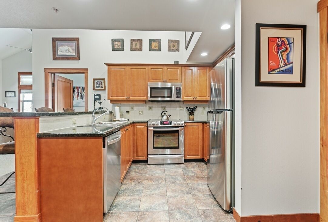 A modern kitchen with wooden cabinets, stainless steel appliances, and a tiled backsplash.