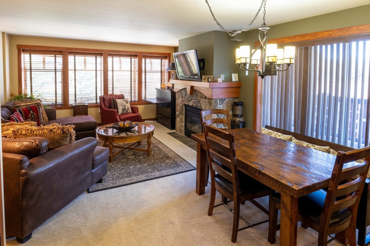 A living room with a fireplace, a dining table, and a sofa.