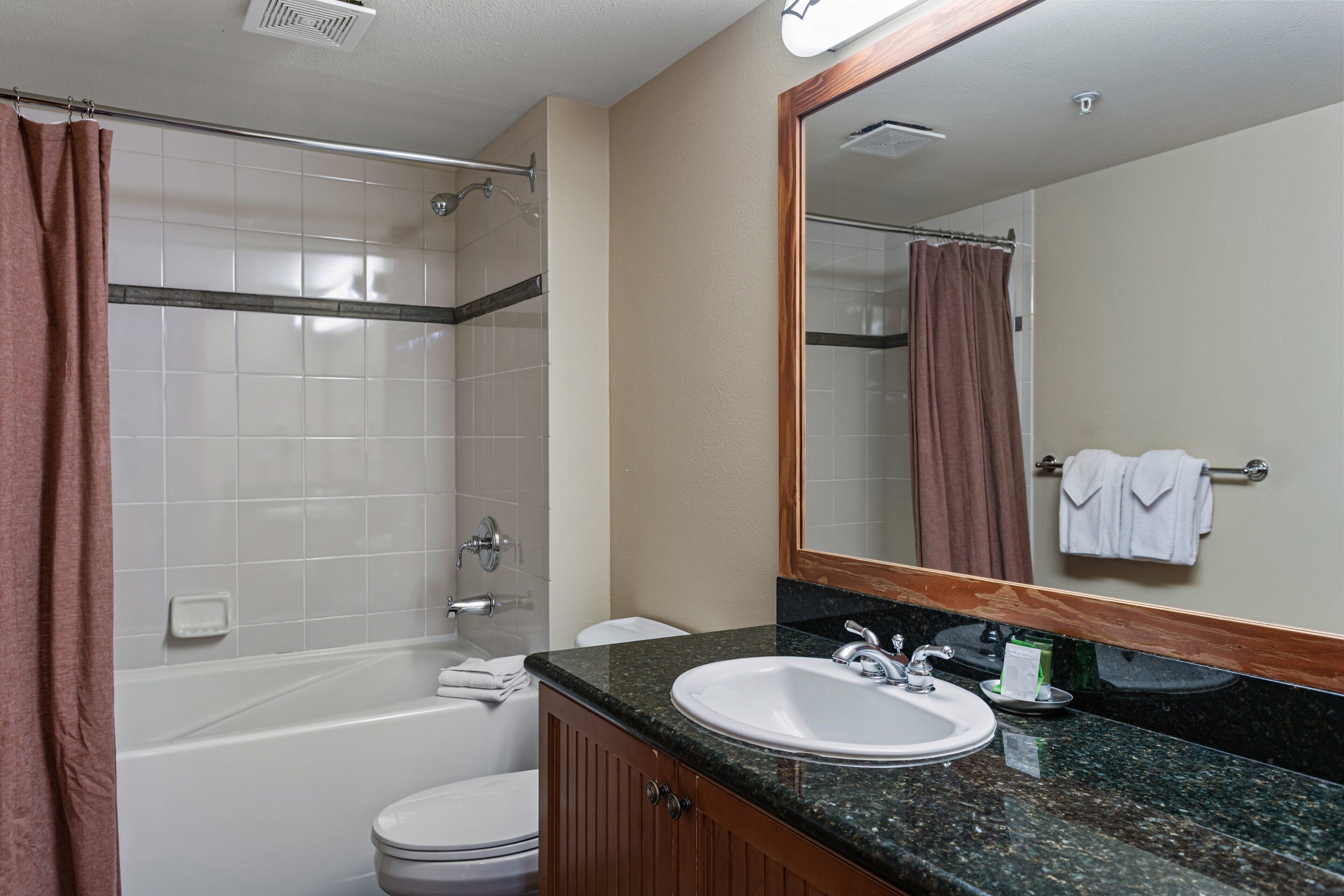 A bathroom with a bathtub, toilet, sink, and a large mirror.