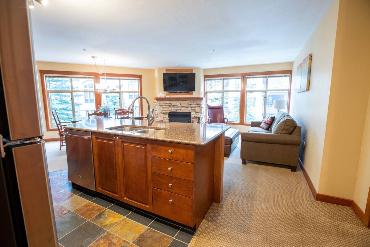 A spacious kitchen with a large island, a built-in fireplace, and a dining area with a sofa.