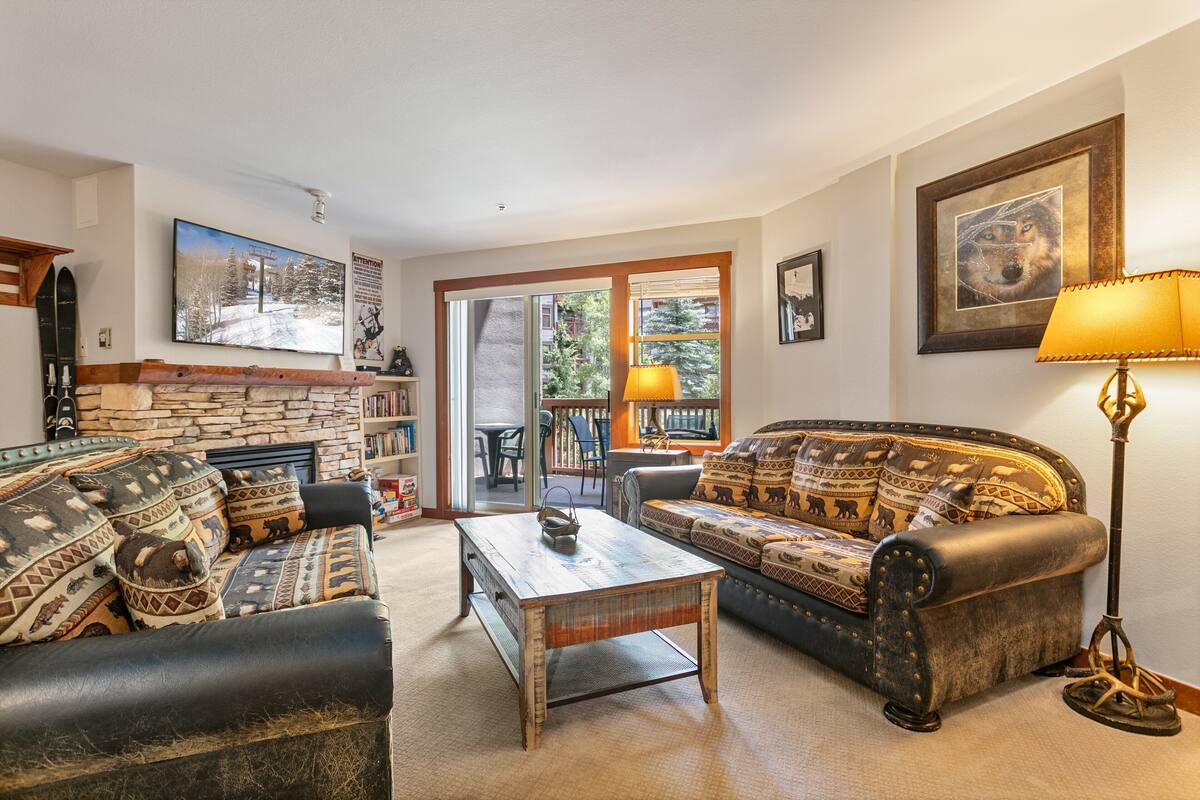A cozy living room with a fireplace, a sofa, a coffee table, and a lamp.