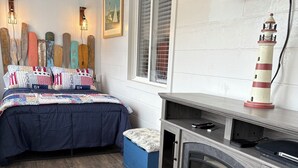 A bedroom with a bed, a fireplace, a television, and a window with blinds.