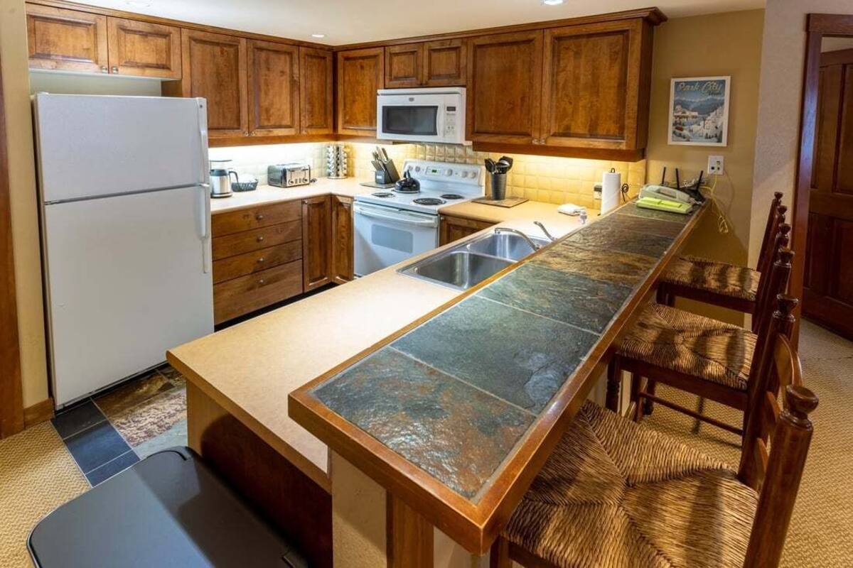 A kitchen with wooden cabinets, a stainless steel sink, a microwave, and a stove.