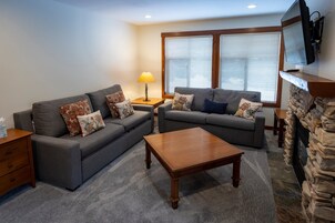 A living room with two grey sofas, a wooden coffee table, and a stone fireplace.
