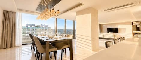 A modern dining area with a long table, chairs, and a chandelier.