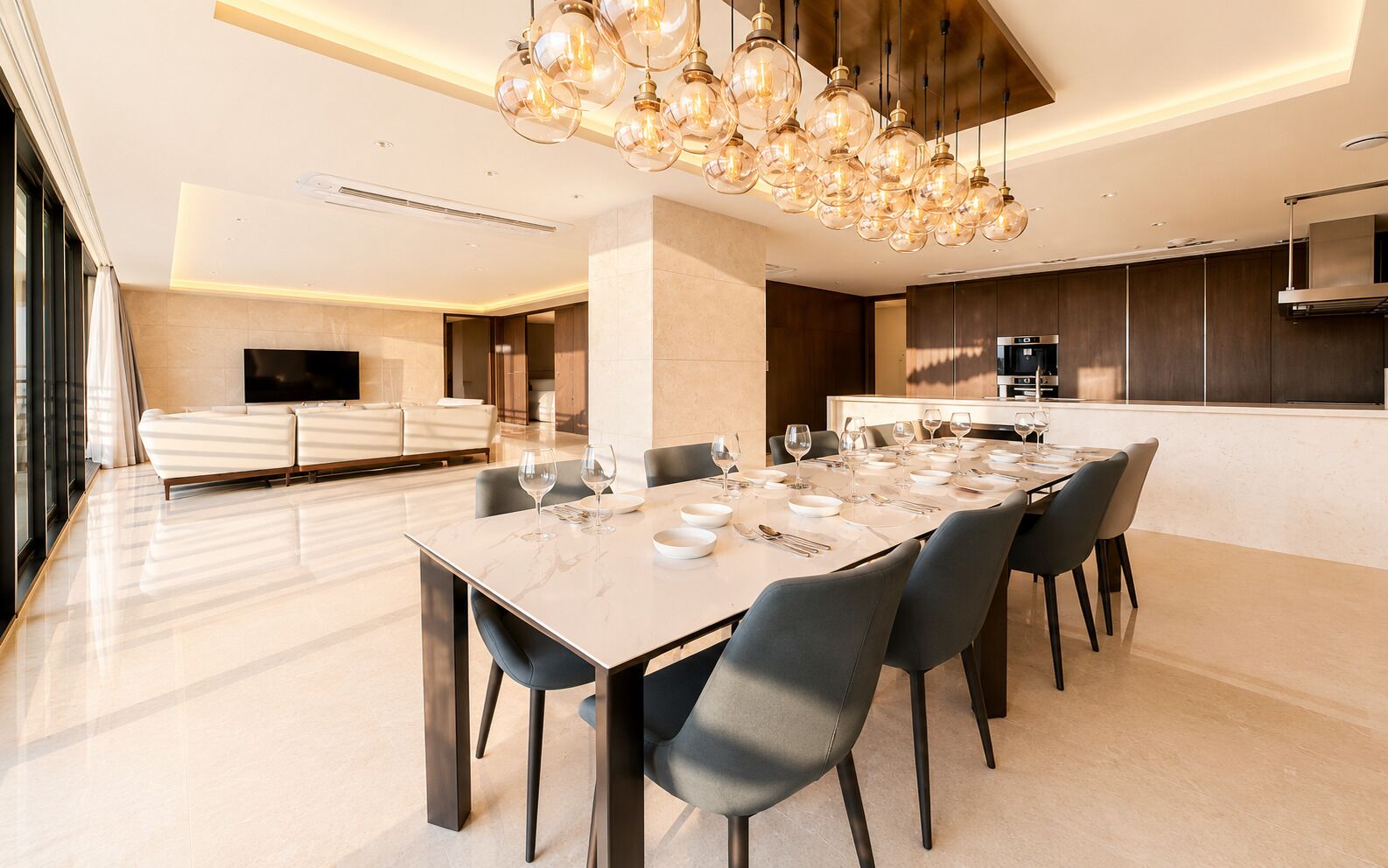 A modern dining area with a marble table set for six, surrounded by chairs.