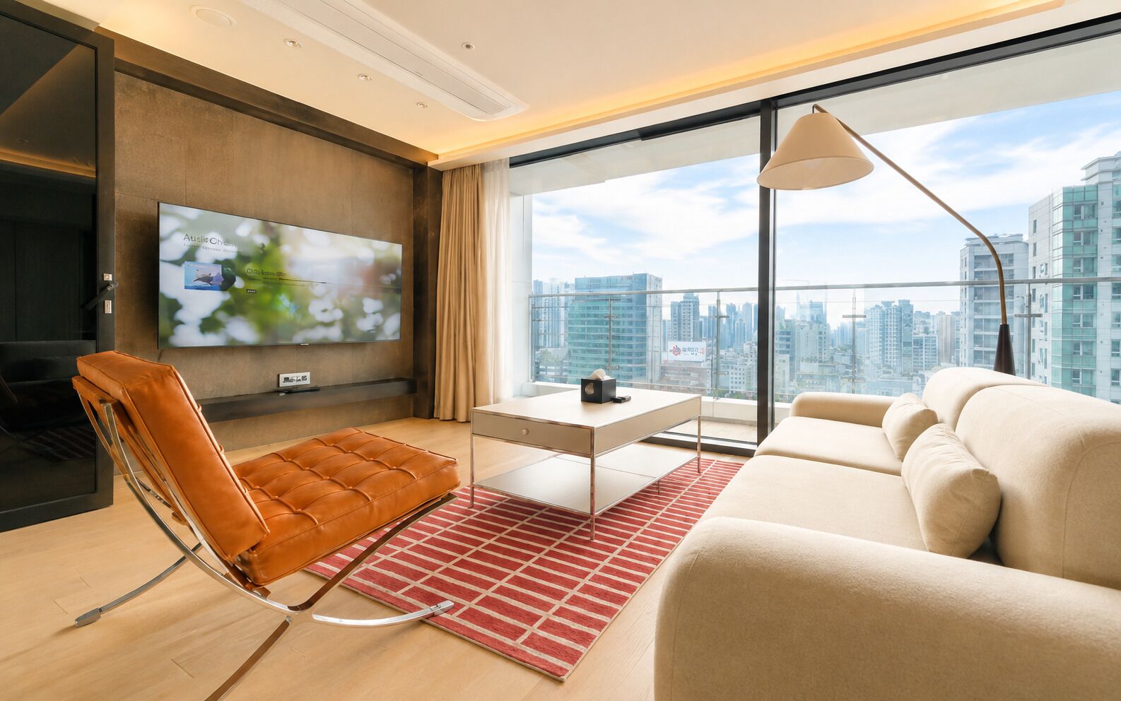 A modern living room with a sofa, a leather chair, a coffee table, and a TV mounted on the wall.