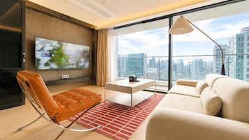 A modern living room with a sofa, a leather chair, a coffee table, and a TV mounted on the wall.