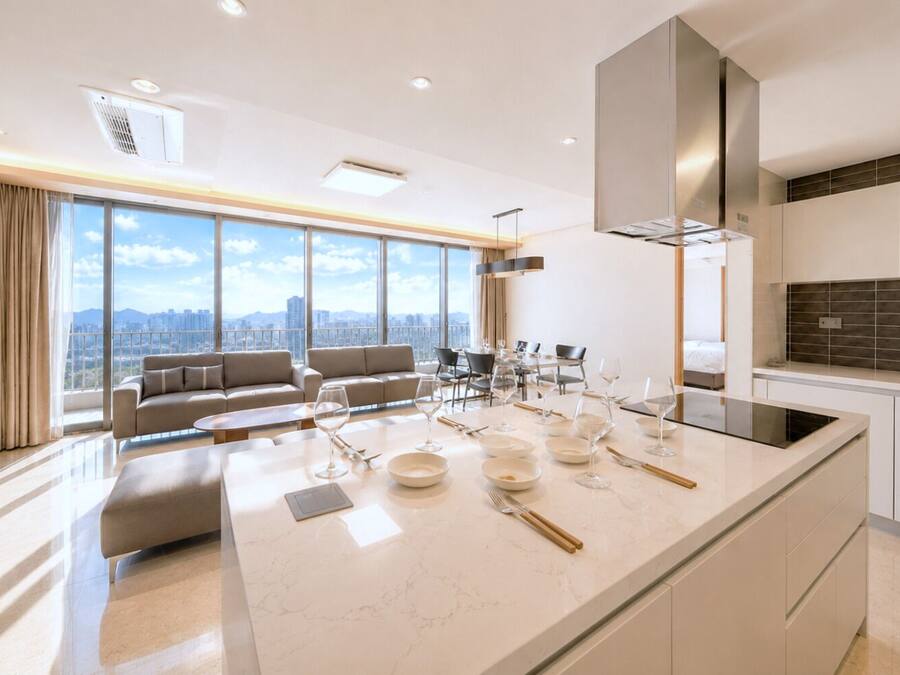 Una cocina moderna con una isla central, comedor con sillas y un sofá.