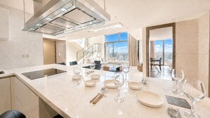 A modern kitchen with a marble countertop, stainless steel appliances, and a dining area with a view. - UH FLAT SIGNATURE DAEGU (Daegu)