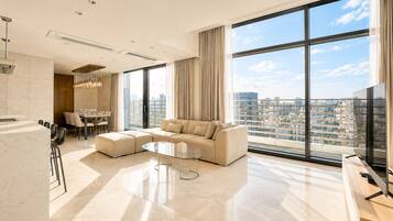 A modern living room with a sectional sofa, a dining area, and a large window with a city view.