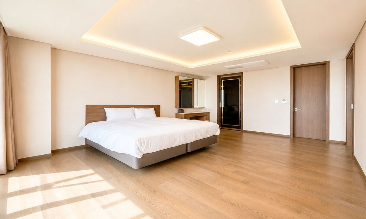 Una habitación de hotel moderna con una cama grande, una mesita de noche, un espejo y un armario.