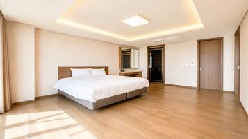 Una habitación de hotel moderna con una cama grande, una mesita de noche, un espejo y un armario.
