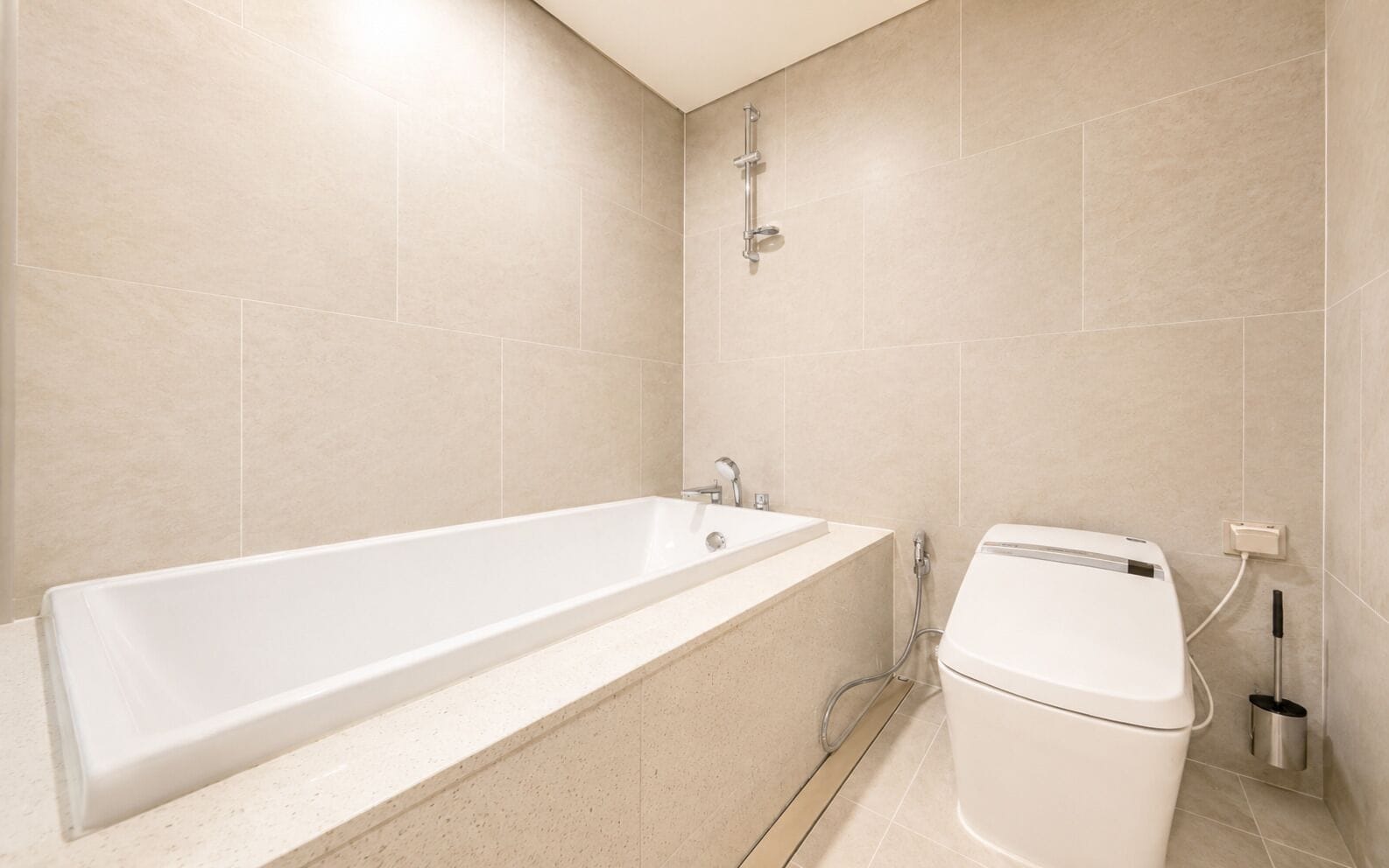 A bathroom with a bathtub, a toilet, and a showerhead.