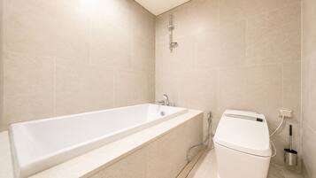 A bathroom with a bathtub, a toilet, and a showerhead.