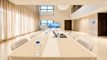 A conference room with a long table, chairs, water bottles, a laptop, and a television screen.