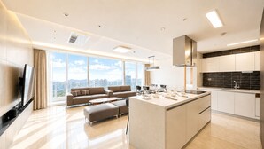 A modern kitchen with a central island, large windows, and a city view. - UH FLAT SIGNATURE DAEGU (Daegu)