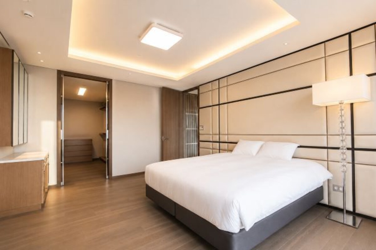 A modern bedroom with a large bed, bedside table, and a lamp.