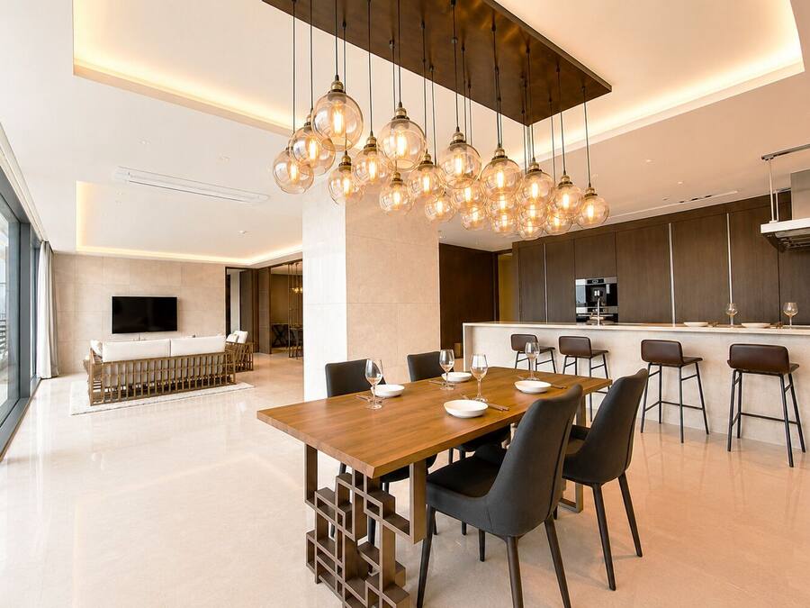 A modern kitchen with a dining area, a bar, and a large window offering a city view.