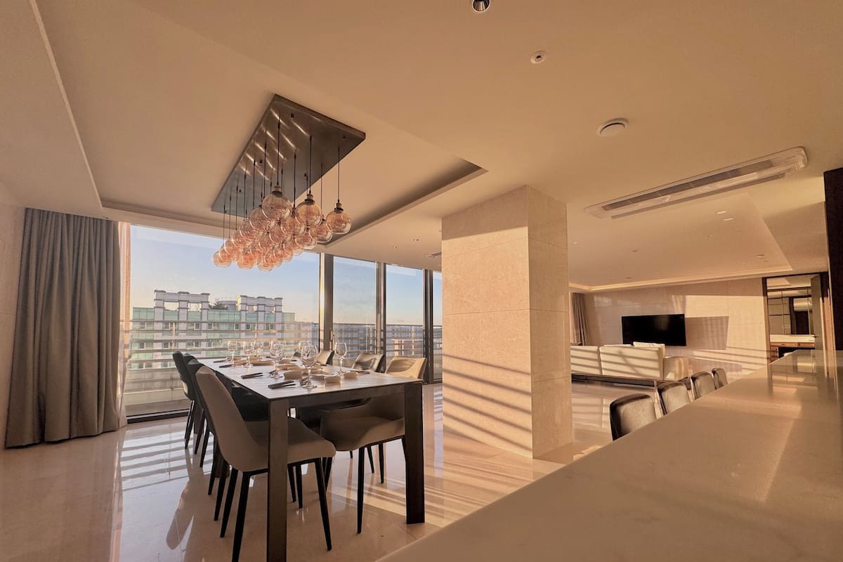 Un espace de salle à manger moderne, avec une grande table, des chaises et un lustre.