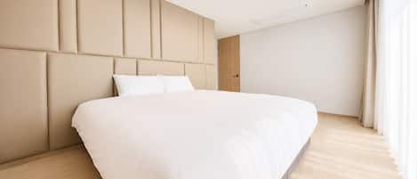 Un dormitorio moderno con una cama grande, un cabecero de paneles verticales, una lámpara de techo y una puerta.