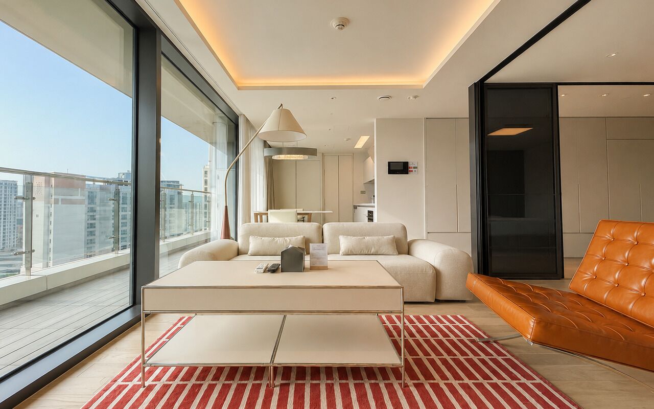 A modern living room with a sofa, a coffee table, and a view of the city.