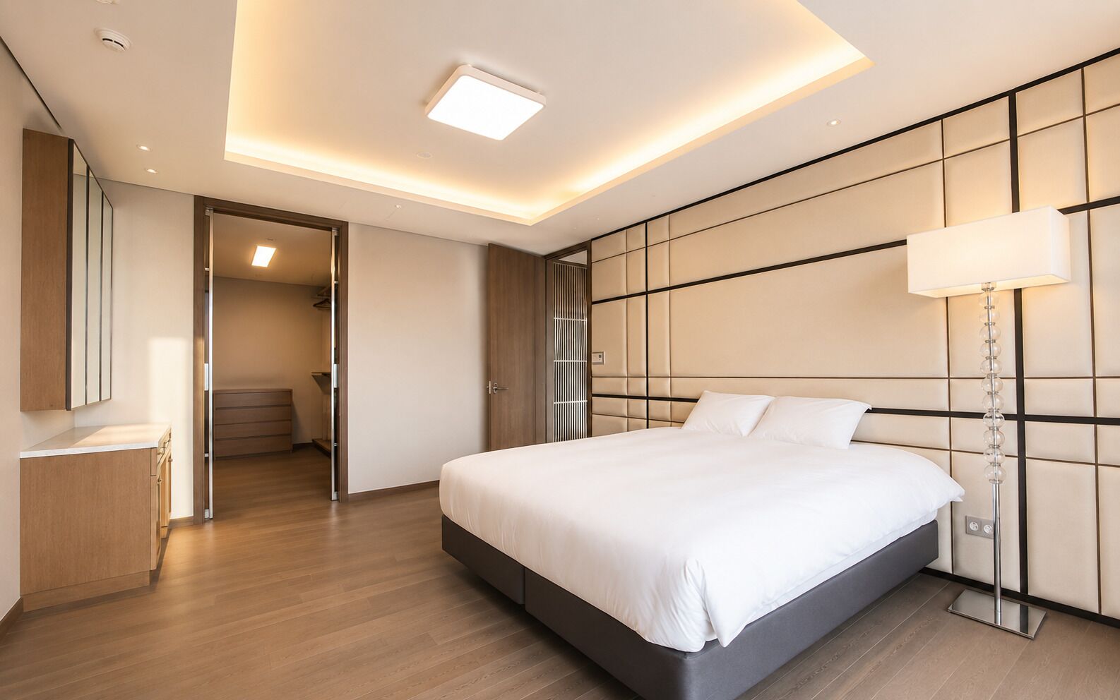 A modern hotel room with a large bed, a bedside lamp, and a wardrobe.