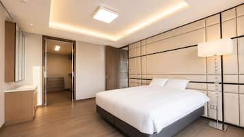 A modern hotel room with a large bed, a bedside lamp, and a wardrobe.
