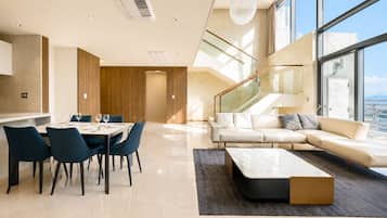 Una sala de estar moderna con un sofá, una mesa de comedor con sillas y una escalera que lleva a un piso superior.