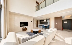 A modern living room with a flat-screen TV, a coffee table, and a sofa. There is a dining area with chairs and a kitchen in the background. - UH FLAT SIGNATURE DAEGU (Daegu)