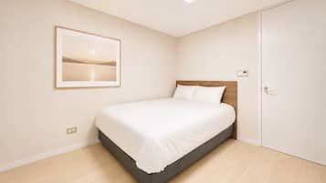 Un dormitorio con una cama, un cuadro en la pared y una puerta.