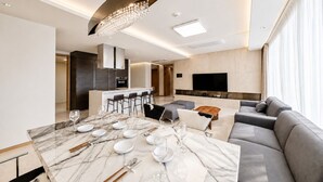 A modern living room with a marble dining table set for four, a grey sofa, and a flat-screen TV mounted on the wall. - UH FLAT SIGNATURE DAEGU (Daegu)