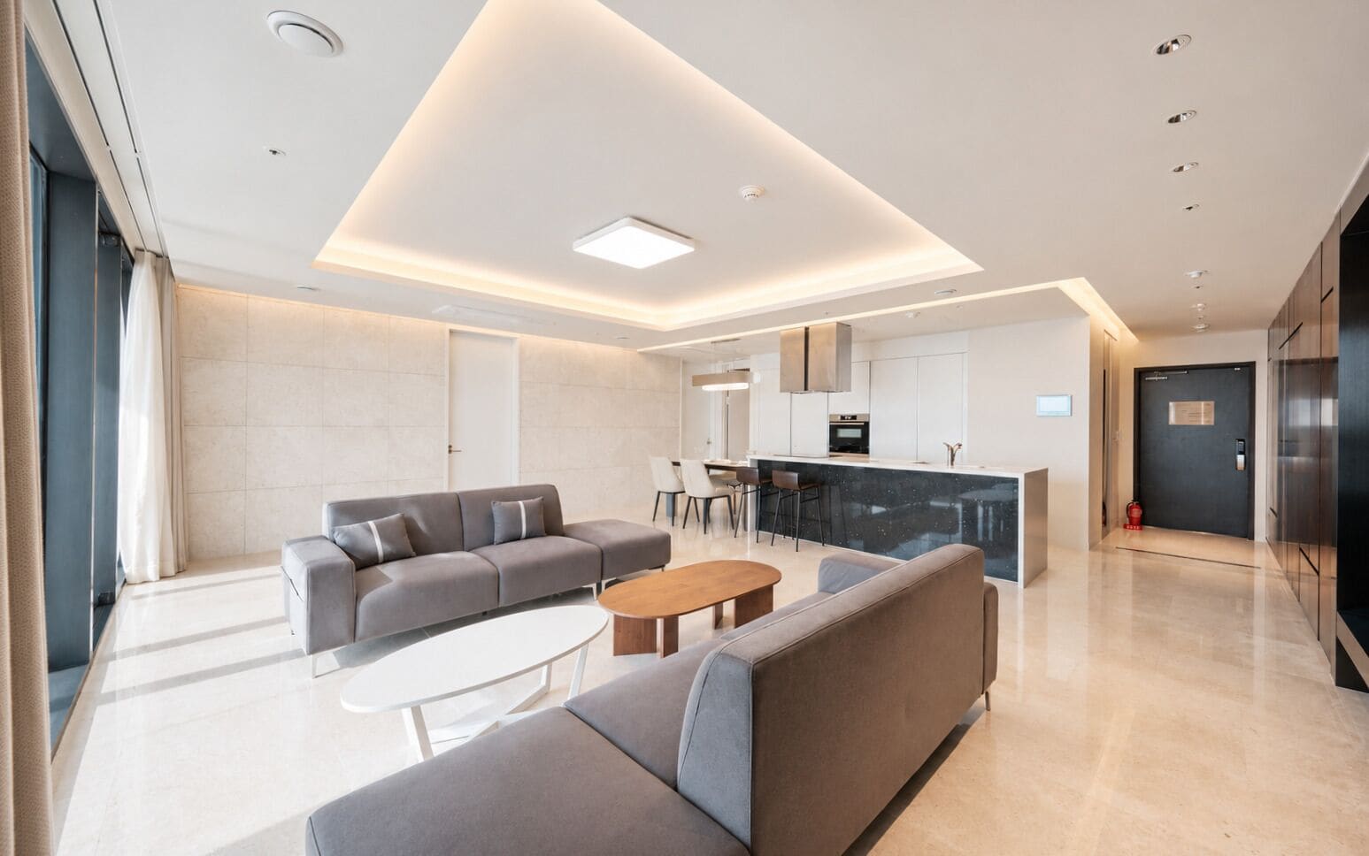 A modern living room with a sofa, coffee table, and a kitchen area with a bar.