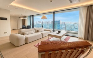 A modern living room with a sofa, coffee table, and a leather bench. - UH FLAT SIGNATURE DAEGU (Daegu)