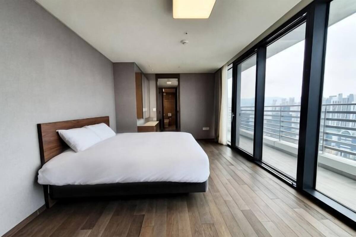 Une chambre d’hôtel moderne avec un grand lit, une vue sur la ville et un plancher en bois.
