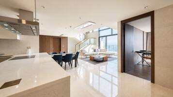 Cocina moderna con encimera de mármol, comedor con mesa y sillas, y sala de estar con sofá y mesa de centro.