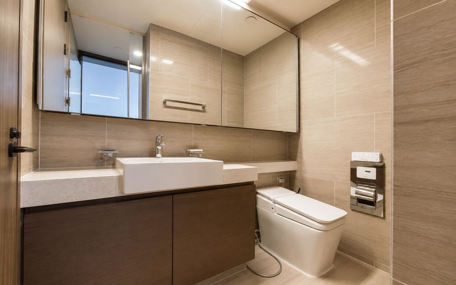 Et moderne badeværelse med et stort spejl, en vask, et toilet og en bidét.
