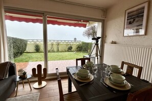 Comedor con una mesa preparada para cuatro, decoración de cactus y vistas a un jardín a través de una puerta corredera.